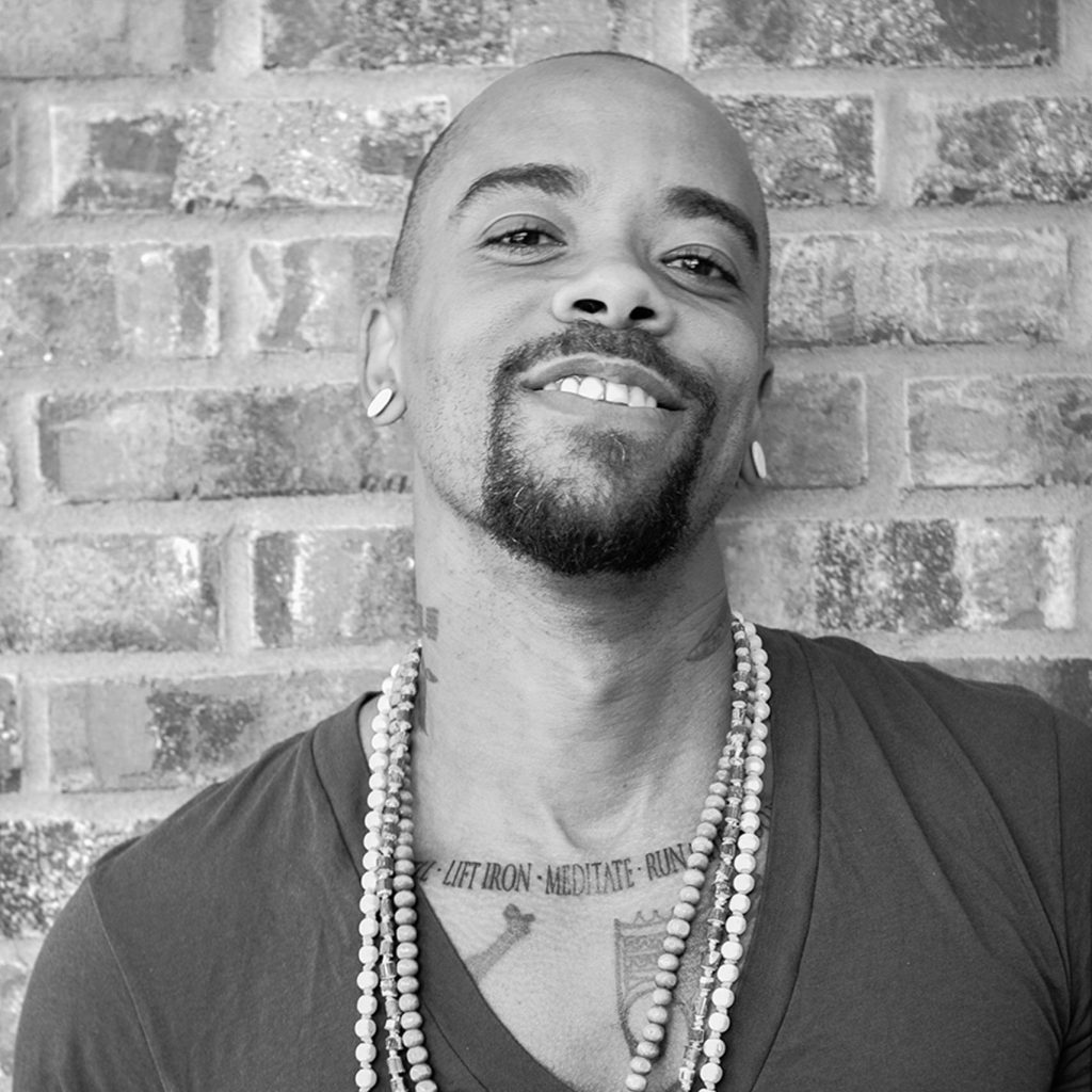 Author Stic smiling and leaning against a brick wall.