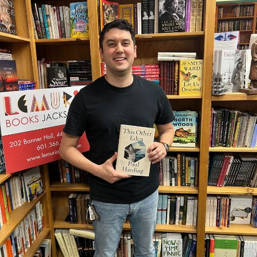 Photo of Bookstagrammer JC Grenn holding the book This Other Eden by Paul Harding in a bookstore.