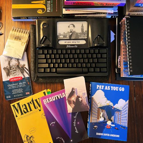 Bookstagram photo collage. Surrounding a modern typewriter are four stacks of books and journals. To the left are graphic pencils and pens. In front are three colorful hardcover books and a small journal with two pigeons on the cover. Everything is on a dark hardwood surface.