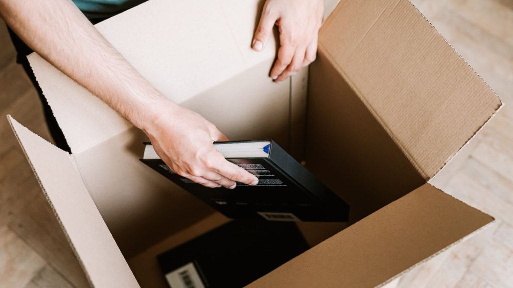 Man storing books in a box.