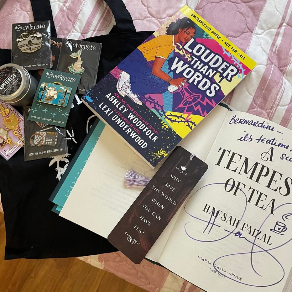 YALLWEST haul with an ARC, signed copy of A Tempest of Tea, bookmarks, a tote bag, and various pins.