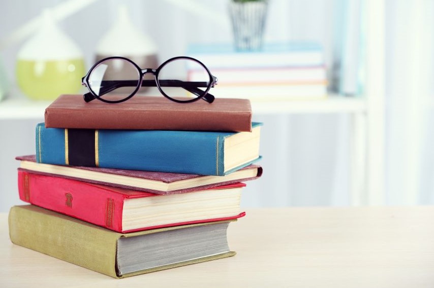A pair of glasses resting on top of a stack of books.