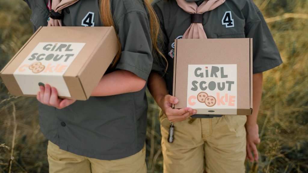 Two girls hold a box labeled "Girl Scout Cookie"