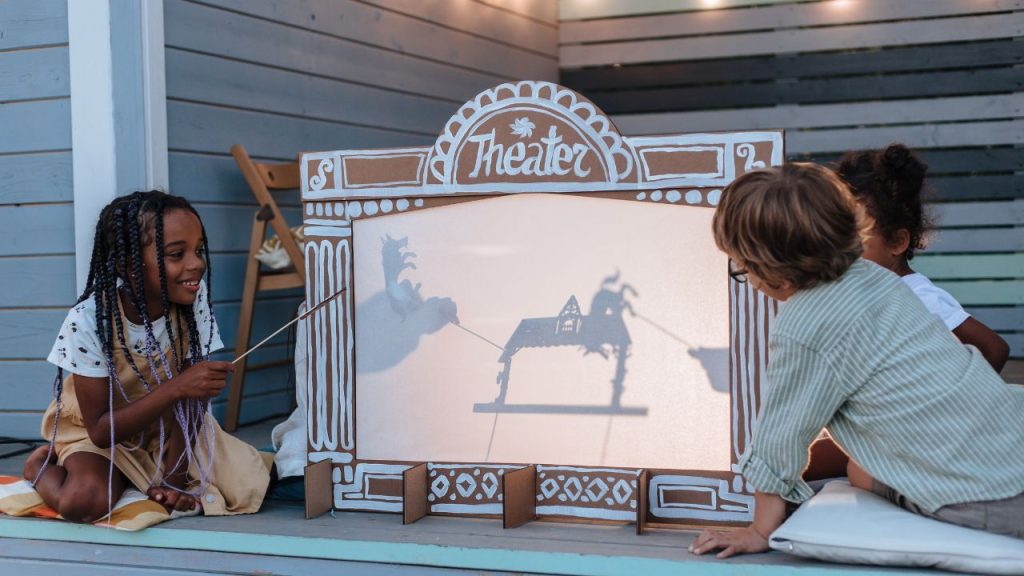 Kids playing and telling a story on a shadow theater.