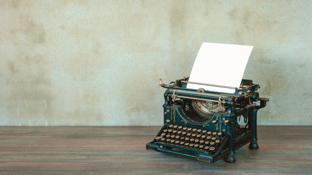 An old-fashioned typewriters sitting on top of a wooden desk.