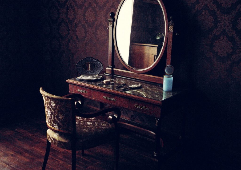 An image portraying a chair and desk arrangement, with a mirror positioned to face the chair. Beauty products are neatly arranged atop the desk.