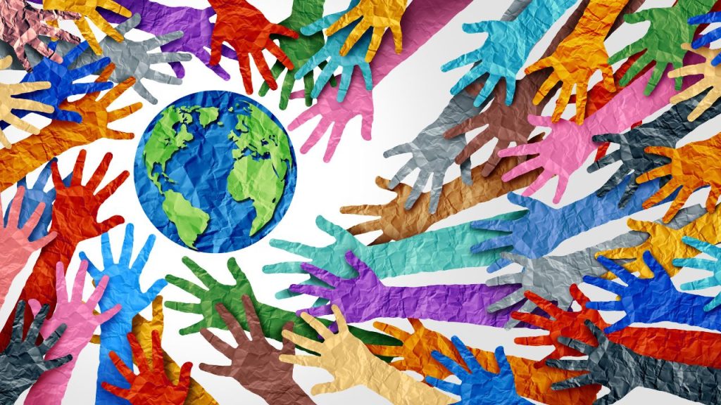Colorful paper hand cut-outs reach out to a paper Earth.