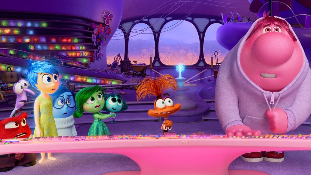Movie still from Inside Out 2 with characters from left to right, Anger, Fear, Joy, Disgust, Envy, Anxiety, and Embarrassment watching as Embarrassment presses buttons on the control panel.