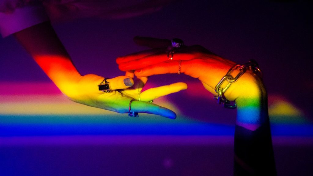 holding hands with a pride flag light