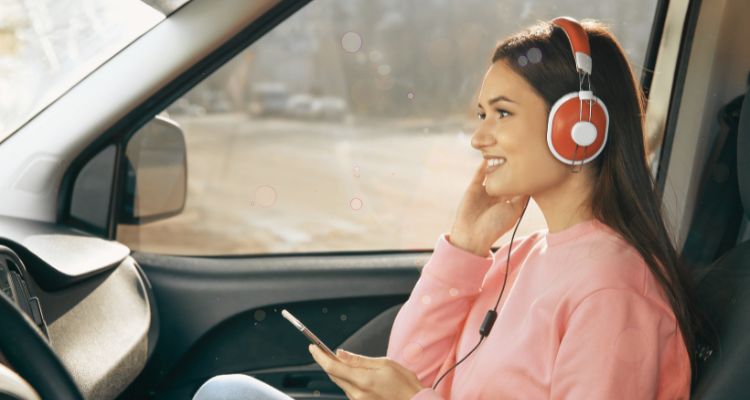 Woman listening to an audiobook on their phone in a car.
