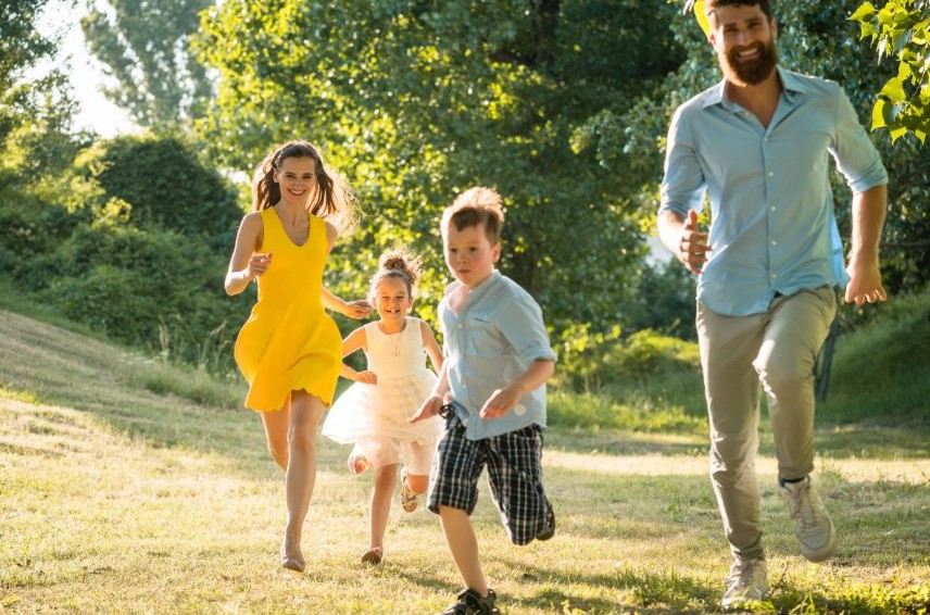 A man, woman, and two children running outside.