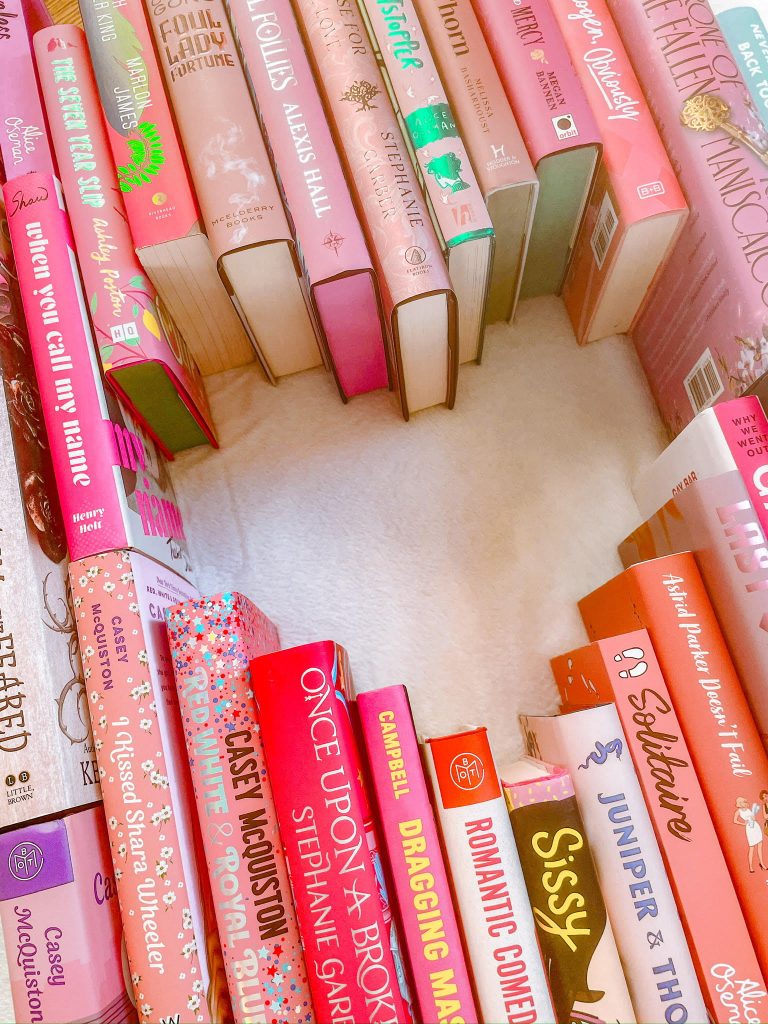 Group of pink books lined in a heart shaped circle.