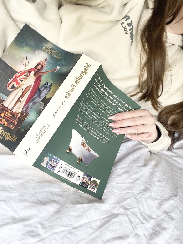 Kaitlyn @kaitlyns_library in bed reading Magnolia Parks Into the Dark
