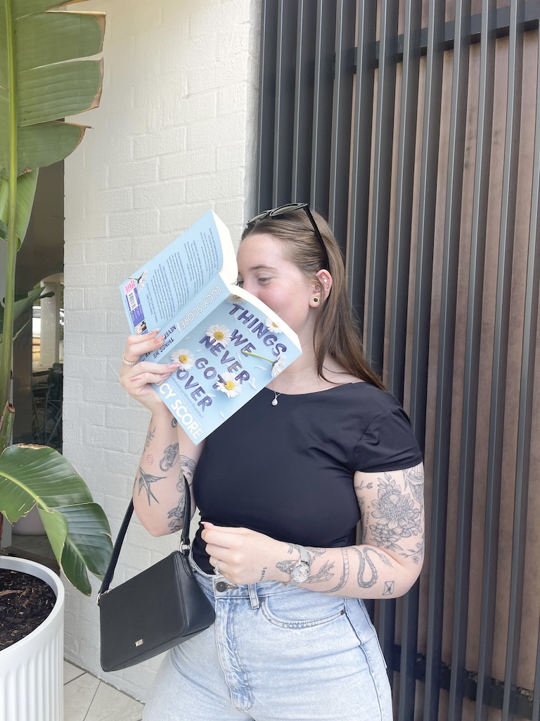Kaitlyn @kaitlyns_library covering her face with Things We Never Got Over.