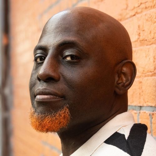 LGBTQ Author Brad Walrond head shot against a brick building.