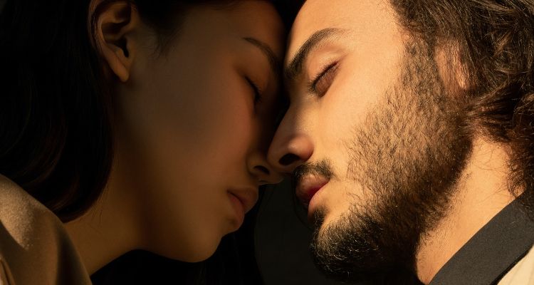Two people -- a man and a woman-- with their eyes closed about to kiss.