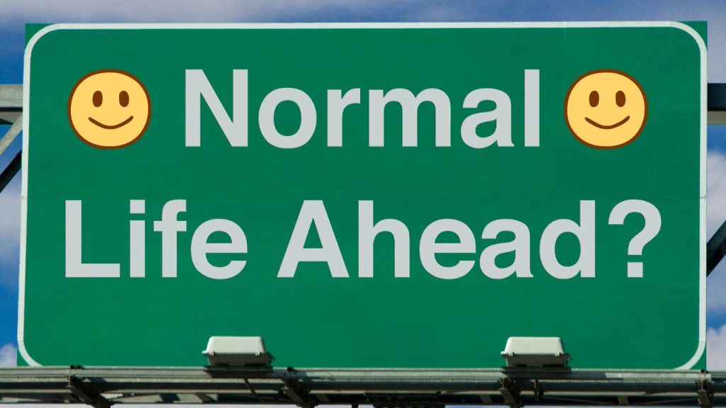 Green road sign with the words "Normal Life Ahead?' with two smiley faces on either side of the sentence.