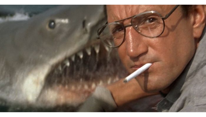 Man with cigarette in mouth before a terrifying shark in Jaws.