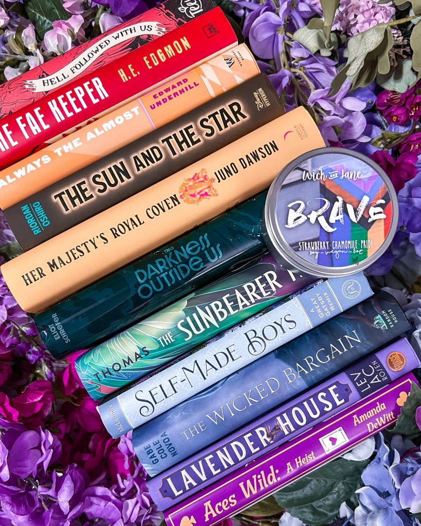 Book titles arranged in a rainbow order on a floral background with a candle called Brave.