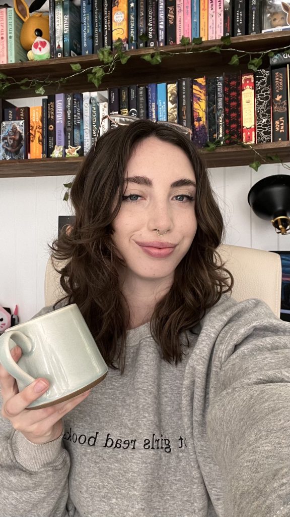 Ruby holding a gray coffee mug and smiling.