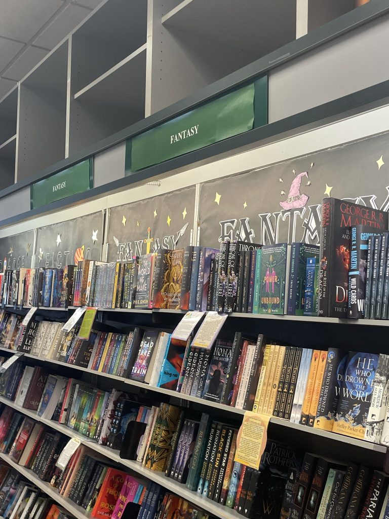 A bookshelf at a bookstore, labeled "Fantasy" at the top in a green sign.