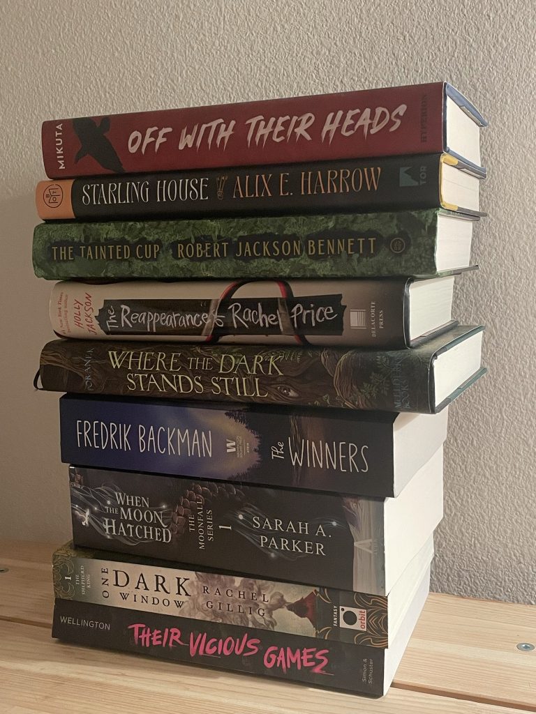 A stack of books sitting in front of a white wall.