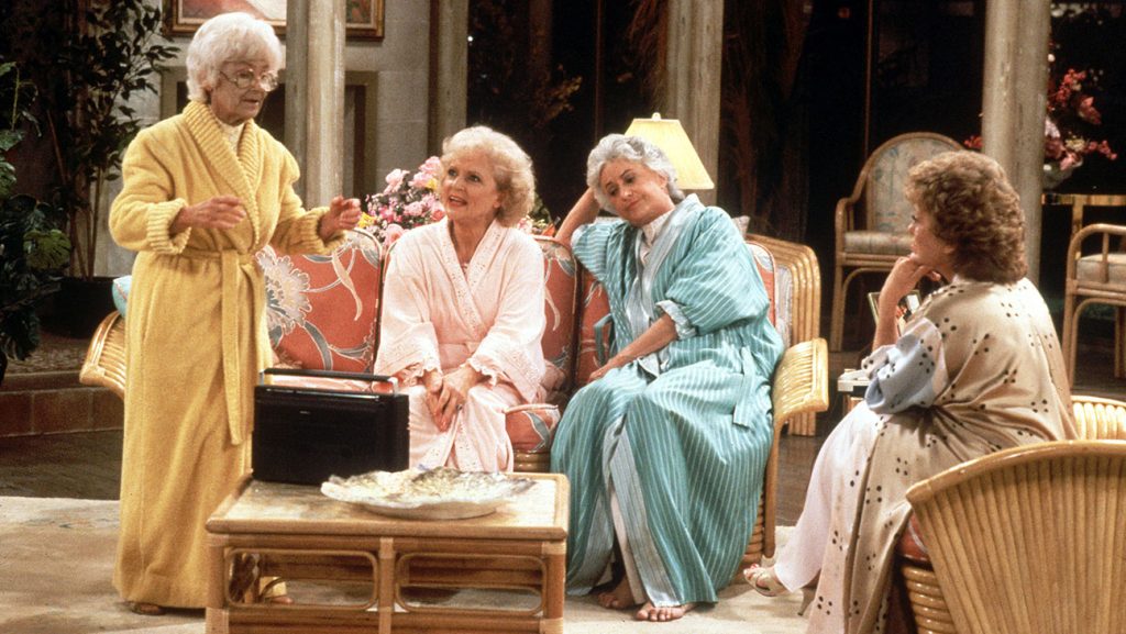 The Golden Girls sitting on the couch and wearing bath robes.