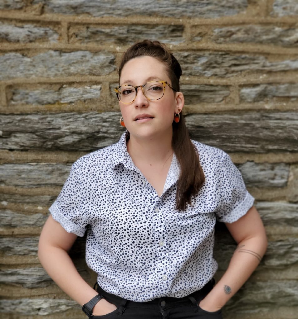 Photo of Sara Nović leaning against a wall, with both hands in her pockets.