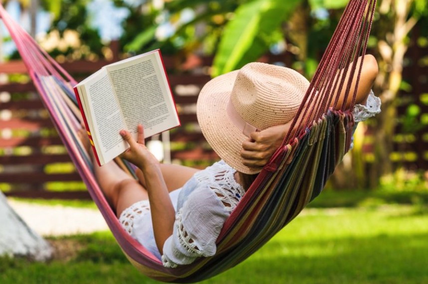Someone reading while resting in a hammock.