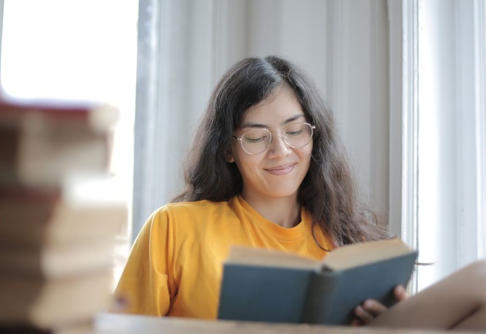 A woman smiling while reading.