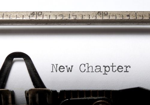 A close-up of a typewriter with the words "New Chapter" printed in black ink on a white page.