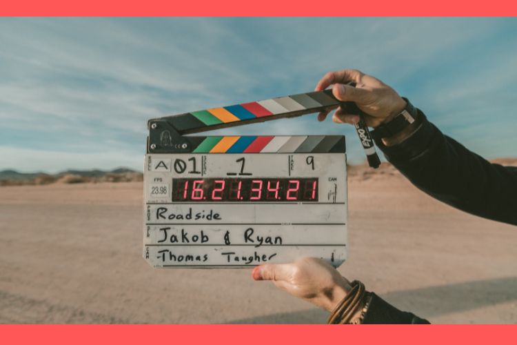 A man standing in the middle of a vast desert, holding a clapperboard ready to be snapped shut.