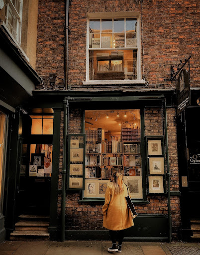 Image provided by bookstagrammer Laura in front of another bookstore with framed images placed on the outside of the bricked store.