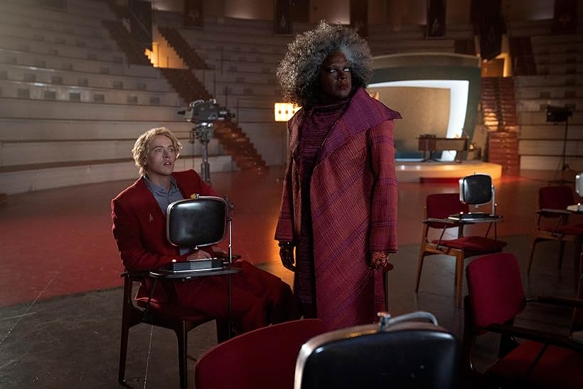 Viola Davis and Tom Blythe, as Dr. Gaul and Coriolanus Snow, respectively, watch a screen.