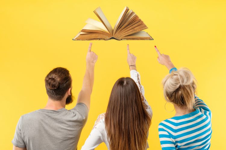 Three people excitedly pointing at a book.