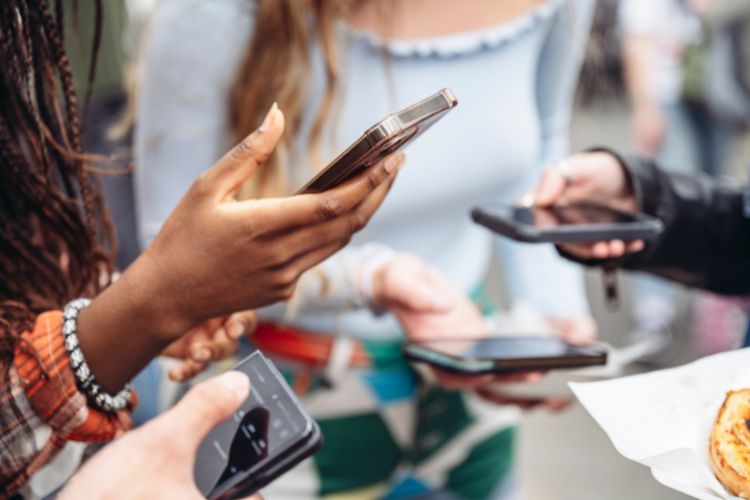 A group of friends scroll through their phones.