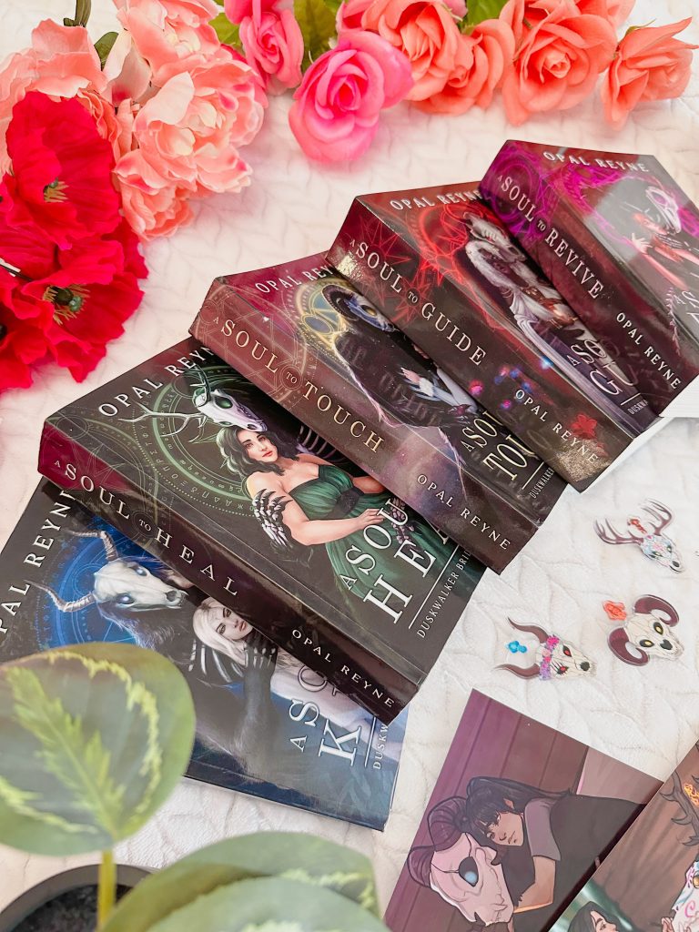 Five books splayed out on a white background, with red/pink flowers behind them. They all have the word "soul" in the name and are by Opal Reyne.