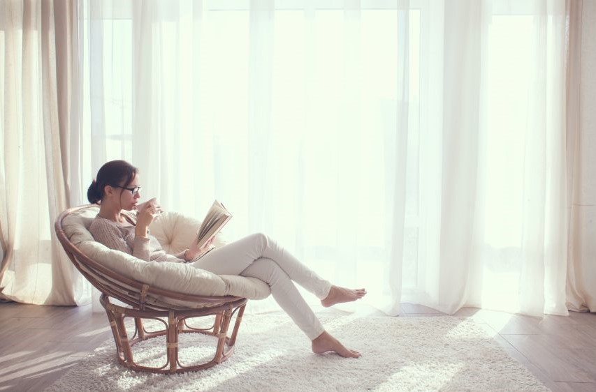 A woman leaning back in a chair and reading.
