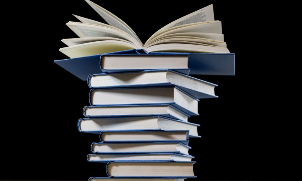 A stack of blue books on a black background. The one on the top is open.