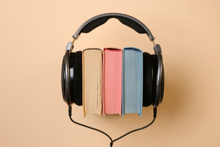 A pair of black headphones contains three books.