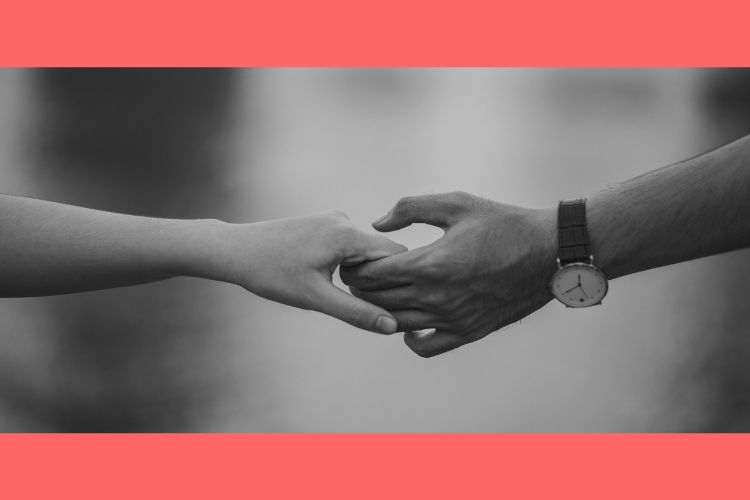 The joined hands of a man and a woman.