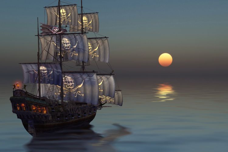 Large ship with pirate flags floating on calm seas with a sun setting in the background