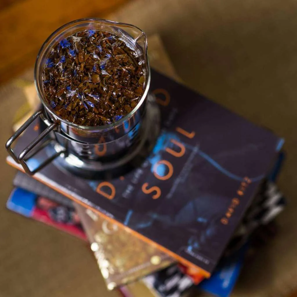 Top view of a cup of coffee centered on top of various books, with the books blurred in the background.