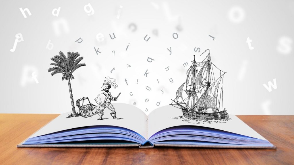 A storybook coming to life, with a blank white book lying open on a brown table. A pirate ship is coming out of the book on the right side, and a pirate, a palm tree, and a treasure chest sit on the left side. Letters float around them.