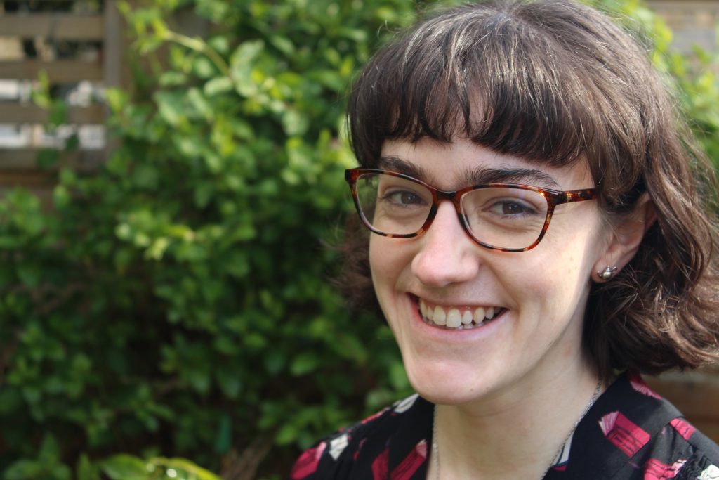 Portrait of author Katie Lumsden outside before a green bush.