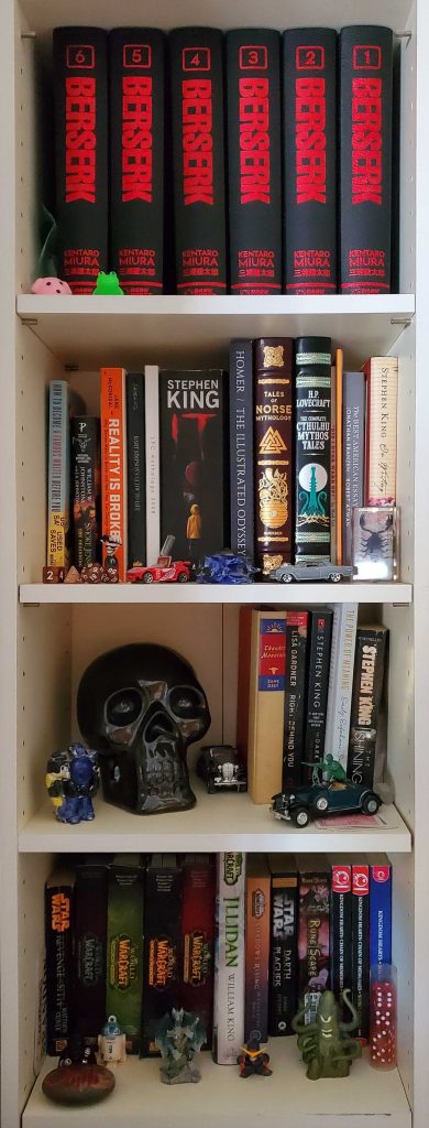 White bookcase stocked with copies of Berserk by Kentaro Miura, a decorative black skull, and miscellaneous figurines.