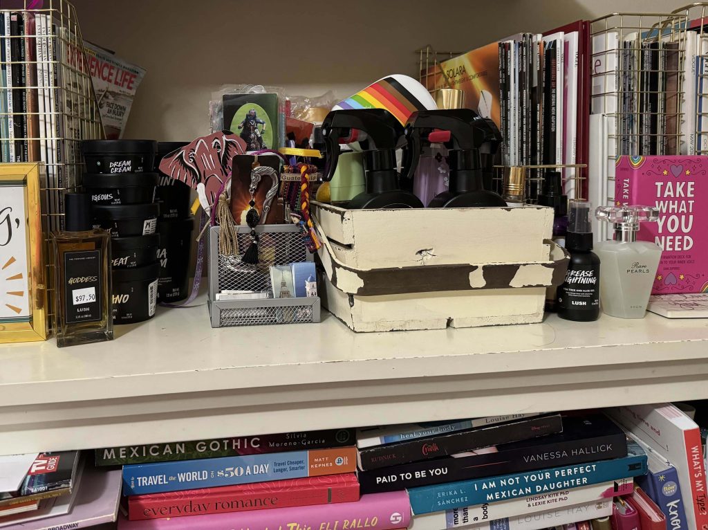 Shelf full of magazine holders, fragrances, and bookmarks. Stacks of books can be seen on the bottom shelf.