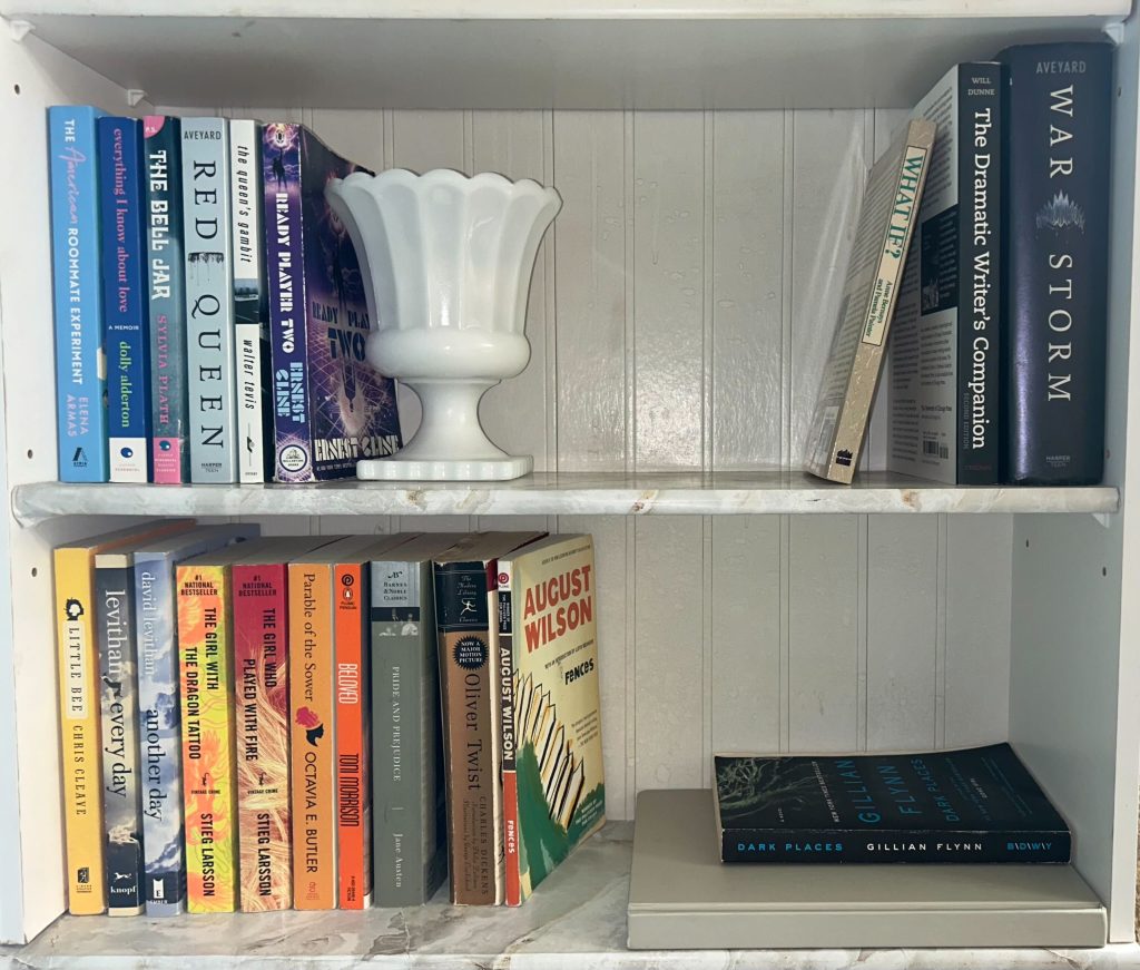 Two marble printed bookshelves with purple and orange books and a white vase.
