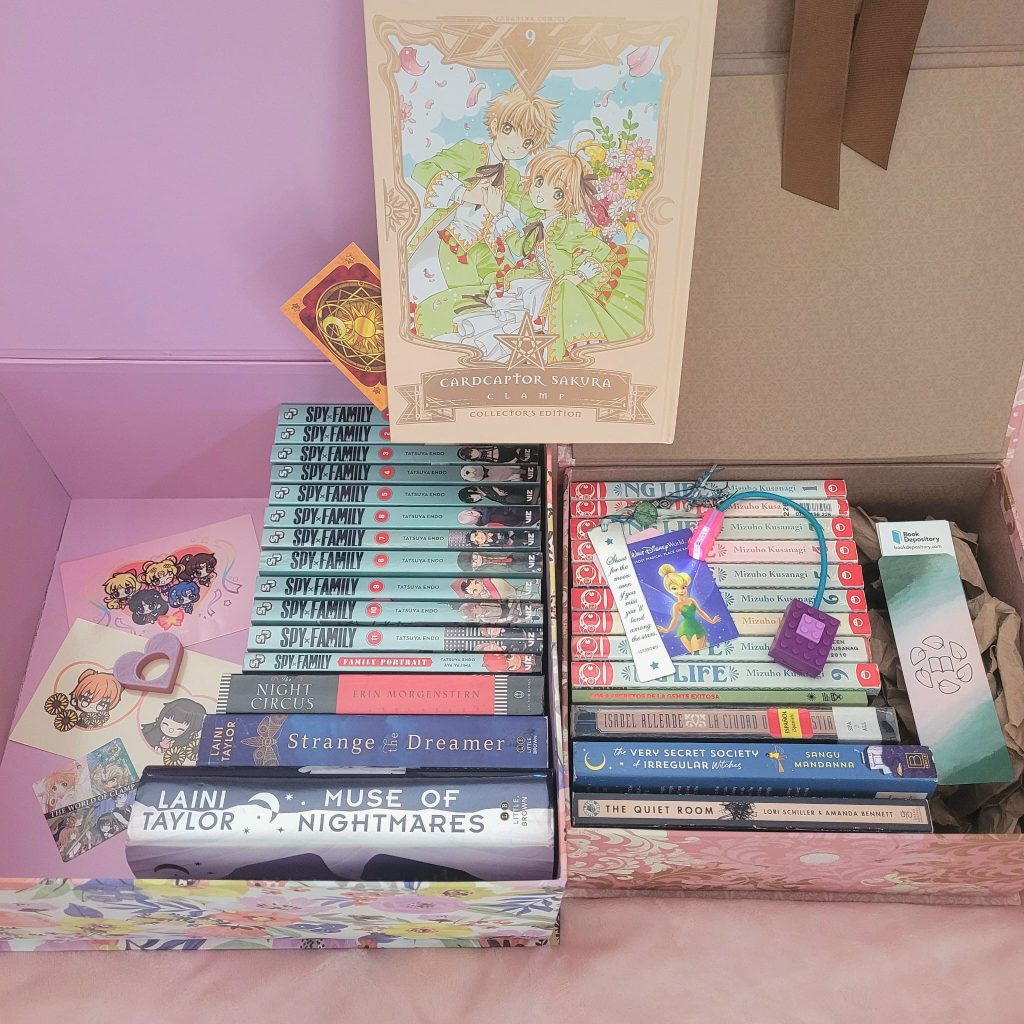 Two open boxes full of books and book accessories. Volume 9 of Clamp's Cardcaptor Sakura, Collector's Ed., stands prominently between both boxes.