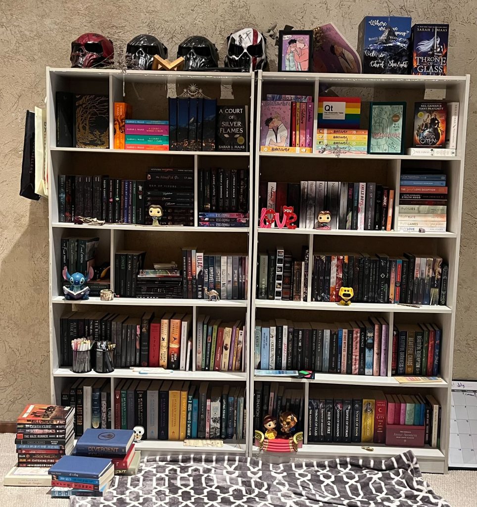 A full white bookcase with a row of skeleton masks propped on top.
